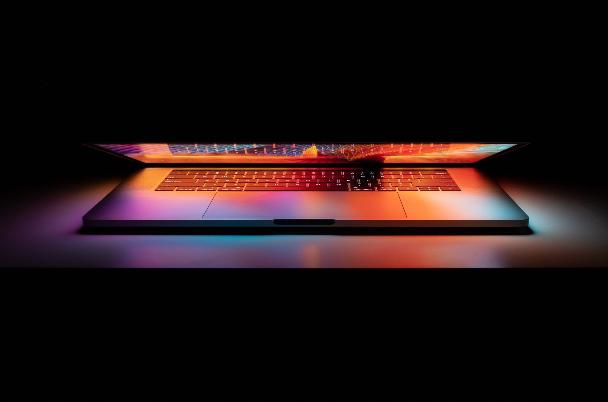 lit up laptop partially closed in dark room