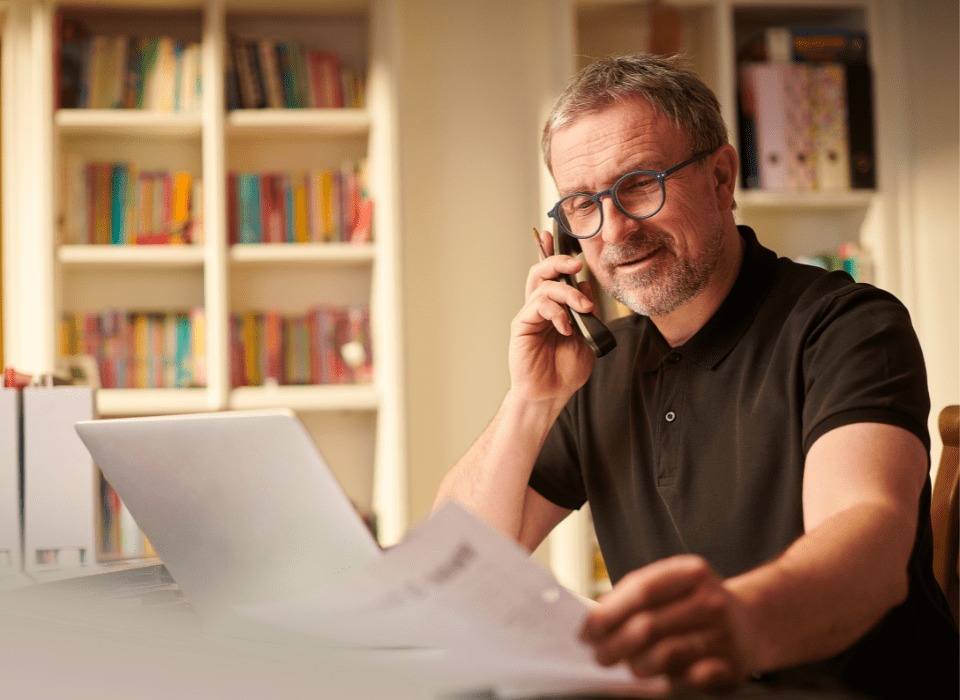 middle aged man looking over documents while talking on the phone