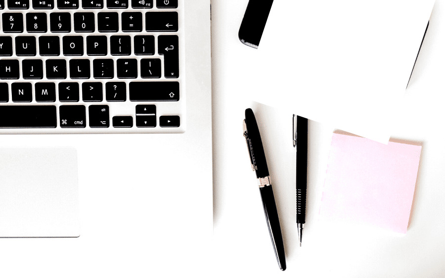 Zoomed in flatlay of a laptop, sticky notes and pens.