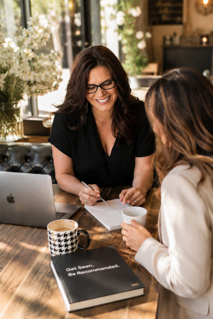 Viv meeting with a client across a desk in a bright office, reviewing notes and discussing ideas.