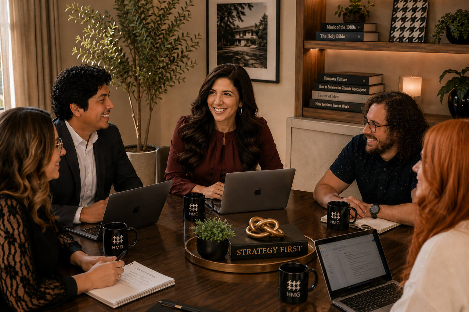 Team meeting around a conference table with laptops, notebooks, and colleagues engaged in discussion.